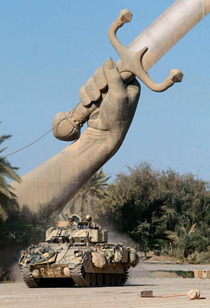 A Bradley fighting vehicle drives under a massive arch of swords, the key symbol of Saddam Hussein and city of Baghdad, Saddam Hussein's military parade grounds, April 11, 2003.